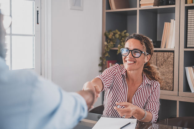 femme RH, souriante, serrant la main à un candidat.